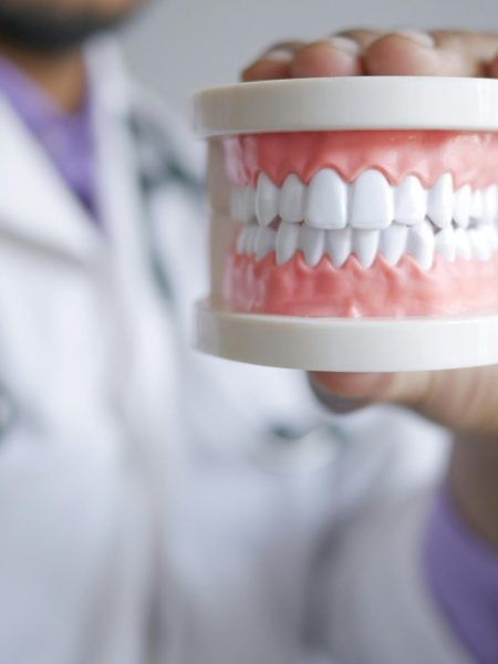 Closeup of a dentist holding a dental prosthetic in a clinical setting, emphasizing prosthodontic care.